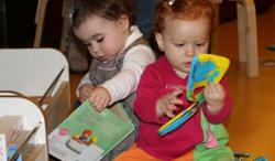 Dúas pequenas desfrutan dos libros no espazo da bebeteca da Biblioteca Municipal Ágora.