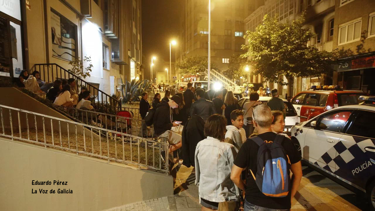 xente dos edificios lindeiros na rúa, mirando o traballo de extinción