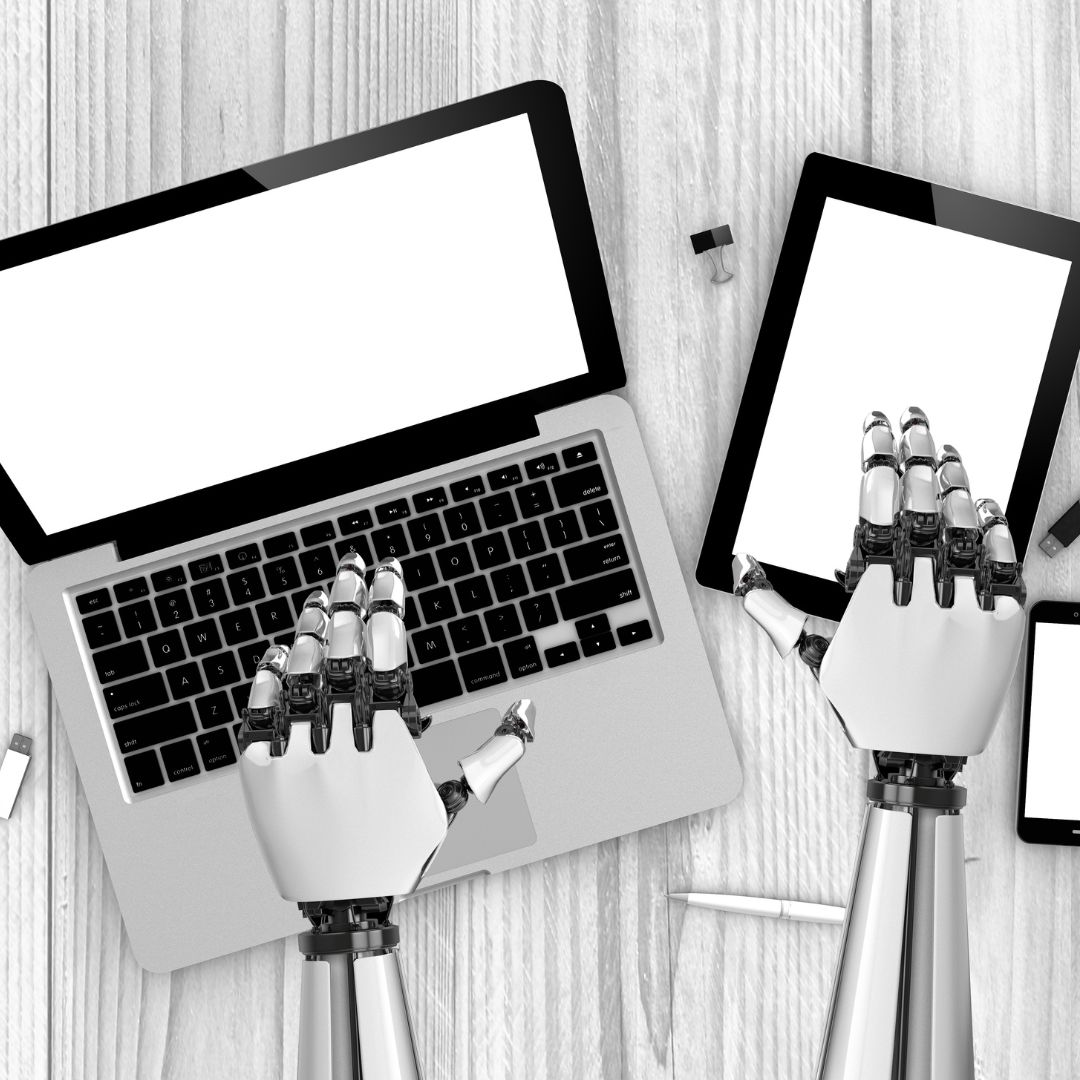 Montaxe das mans dun robot traballando nunha tablet e un portátil.