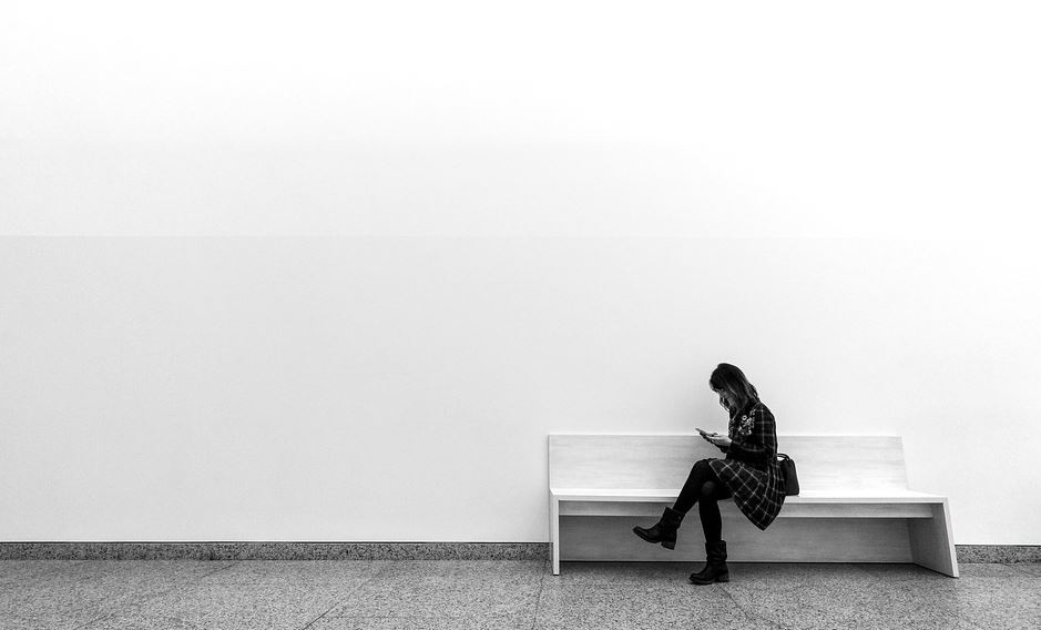 Muller sentada nun banco e mirando o móbil.