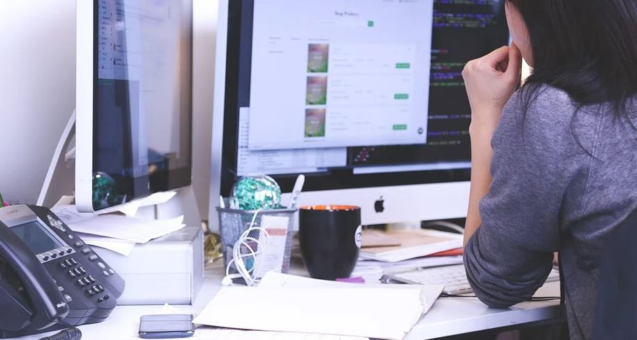 Muller trabalando nunha oficina cun ordenador.