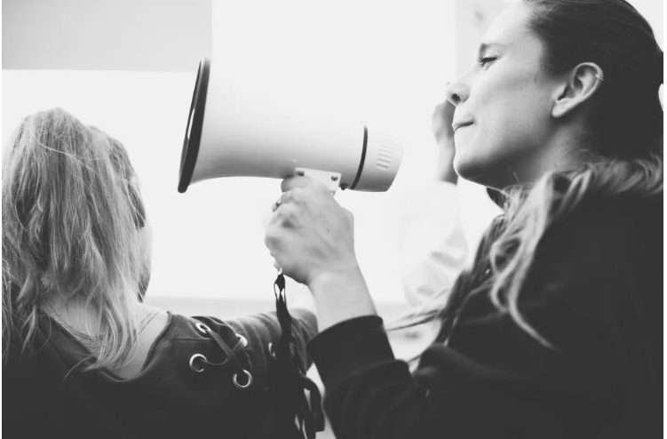 Fotografía dunha muller falando por un megáfono