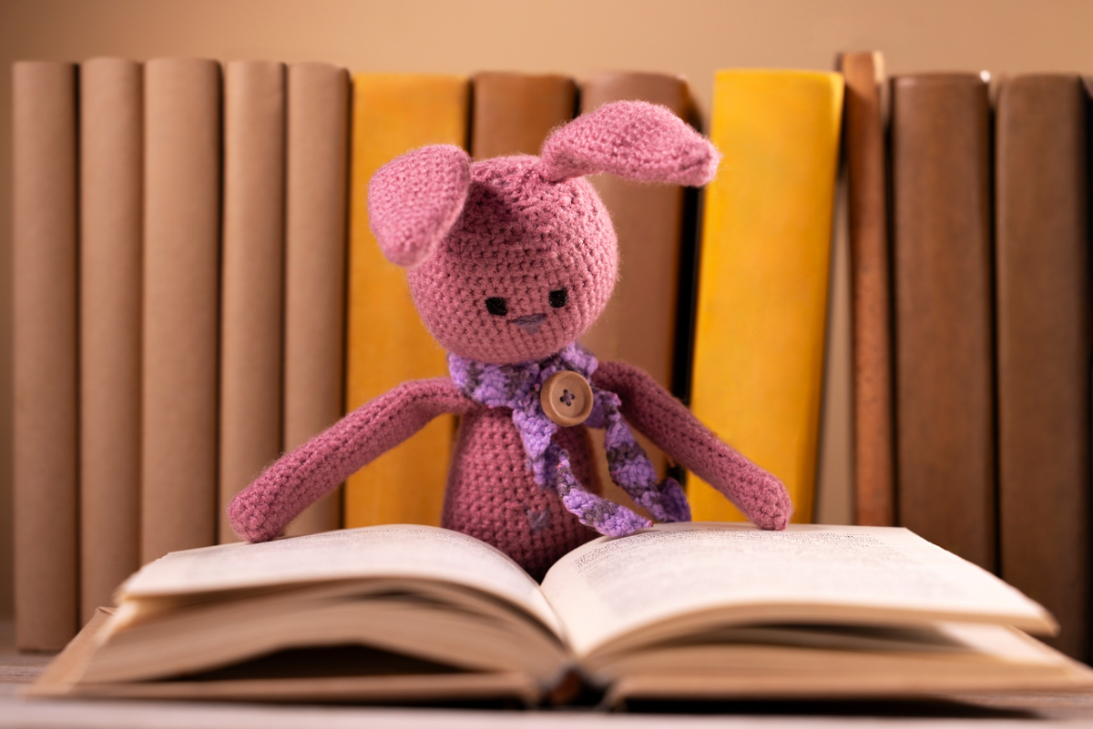 Boneco de coello de ganchillo ollando un libro aberto pola metade