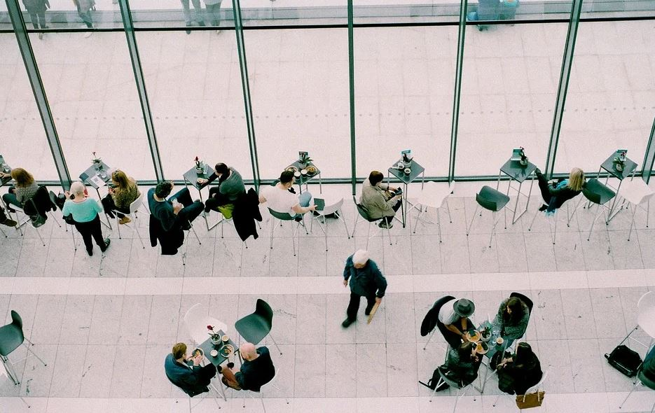 Personas sentadas en mesas hablando y tomando café. 