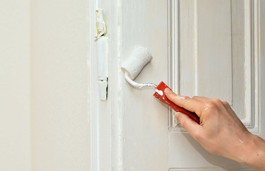 Persoa pintando unha porta.