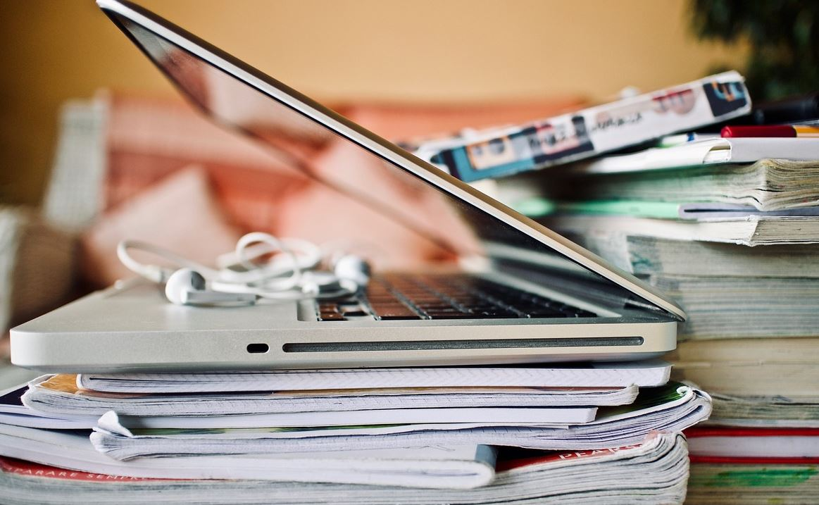Ordenador e carpetas con apuntes e documentos. 
