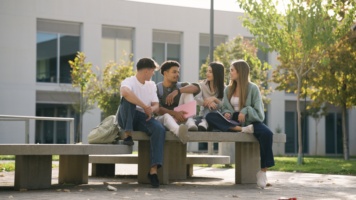 Fotografía duns estudantes sentados nun banco campus.