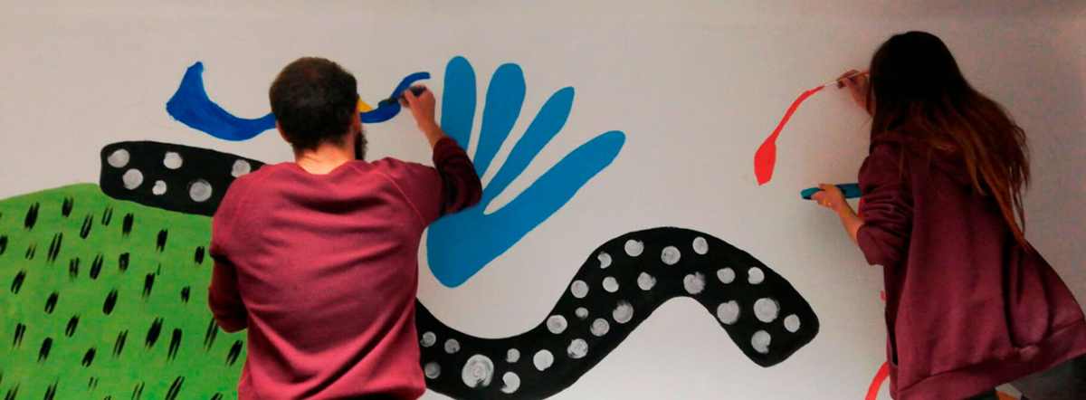 1 par de voluntarios decorando parede con debuxos e pinturas