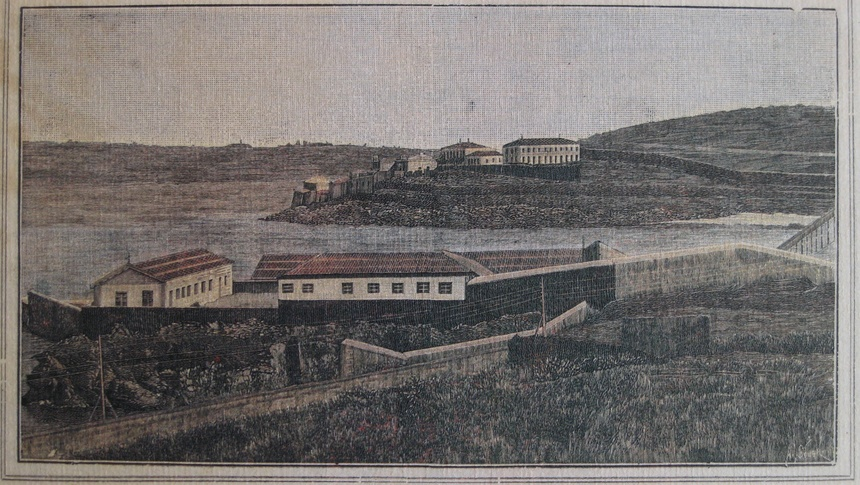A imaxe mostra un gravado ou ilustración histórica do Lazareto de Oza, na Coruña. Trátase dunha vista panorámica dun complexo sanitario situado xunto ao mar, rodeado por altos muros de peche. No primeiro plano obsérvanse varios edificios rectangulares con tellados a dúas augas, encerrados dentro dun recinto amurallado. No fondo pode verse outro conxunto de edificacións situado nun pequeno promontorio costeiro. A paisaxe aparece practicamente despoboada, con terreos abertos e ondulados arredor das instalacións.